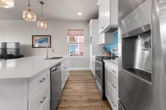 kitchen featuring visible vents, a kitchen island with sink, light wood-style floors, a sink, and appliances with stainless steel finishes
