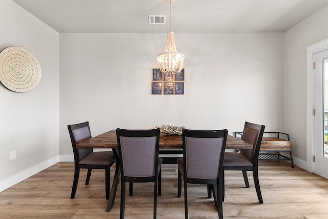 dining room featuring a chandelier, baseboards, visible vents, and light wood-style floors
