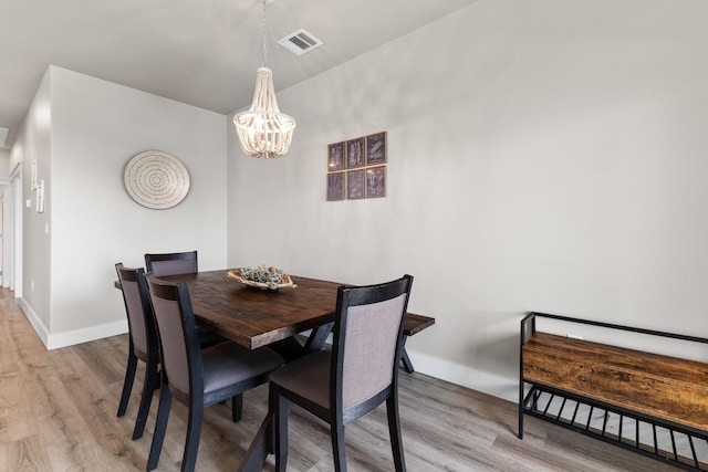 dining room featuring baseboards, visible vents, an inviting chandelier, and light wood finished floors