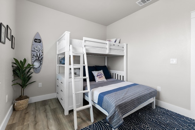 bedroom featuring visible vents, baseboards, and wood finished floors