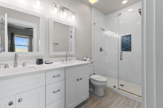 full bath featuring a sink, a shower stall, toilet, and wood finished floors