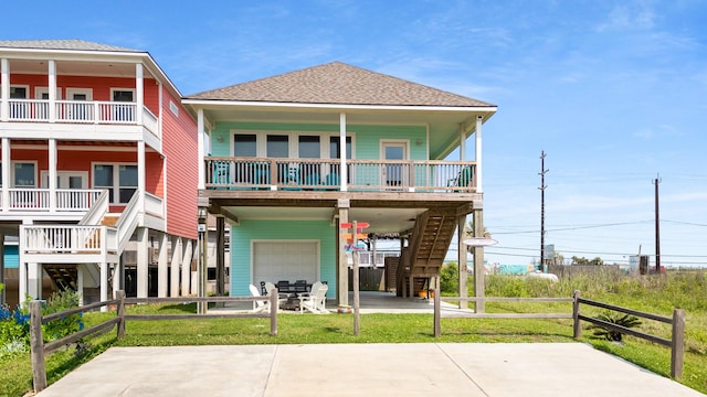 rear view of house with stairs, a shingled roof, an attached garage, driveway, and a carport