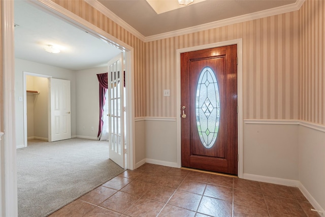 carpeted foyer entrance with crown molding, tile patterned floors, baseboards, and wallpapered walls