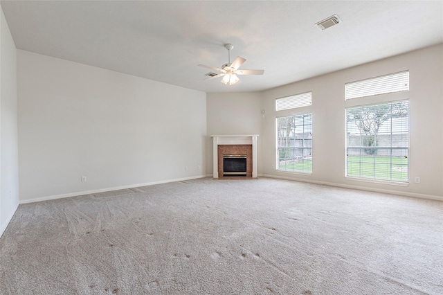 unfurnished living room featuring ceiling fan, carpet floors, a premium fireplace, baseboards, and visible vents