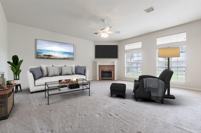 living area with a ceiling fan, visible vents, carpet floors, baseboards, and a premium fireplace