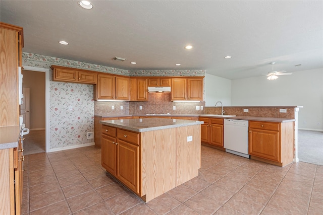 kitchen featuring a sink, baseboards, a peninsula, under cabinet range hood, and white appliances