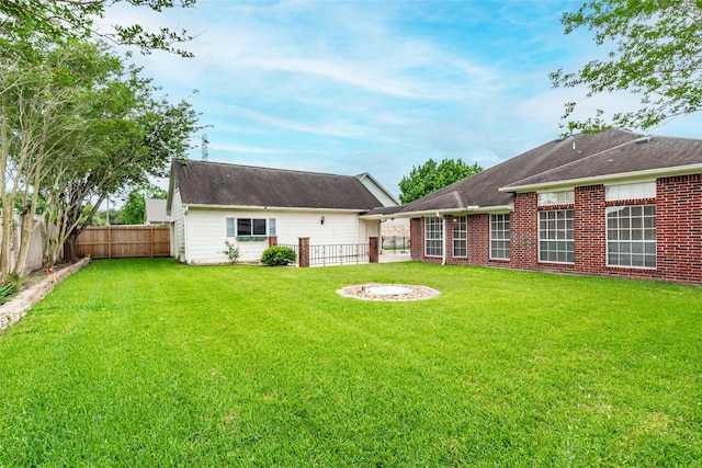 rear view of property with a yard, brick siding, and a fenced backyard