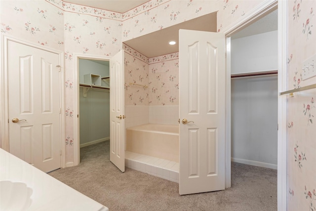 full bathroom with a garden tub, baseboards, carpet floors, a spacious closet, and wallpapered walls