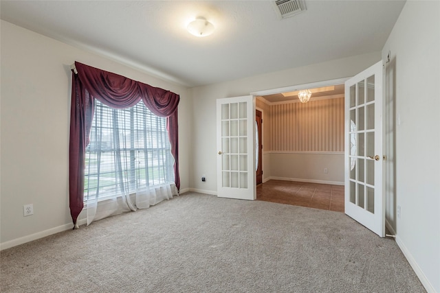 carpeted spare room with baseboards, visible vents, french doors, and an inviting chandelier