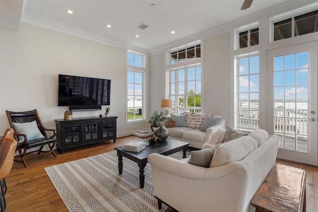 living room with ornamental molding, recessed lighting, wood finished floors, and visible vents