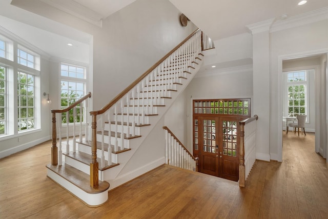 staircase with baseboards, ornamental molding, a wealth of natural light, and wood finished floors