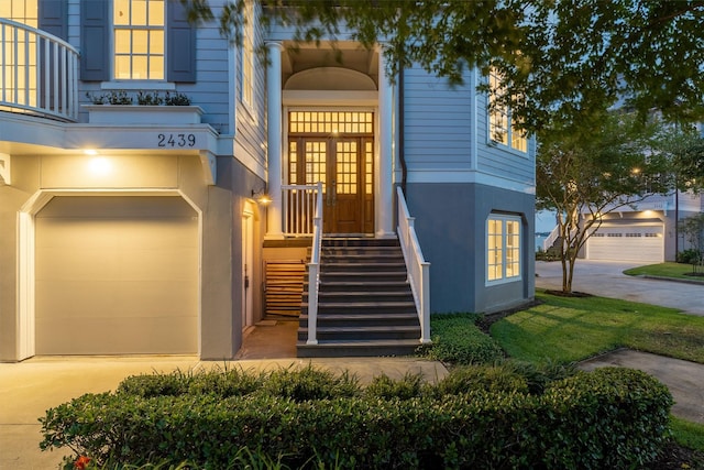view of front of home featuring a balcony, stucco siding, french doors, an attached garage, and driveway