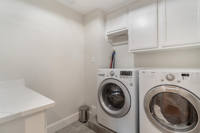 clothes washing area featuring baseboards, cabinet space, light tile patterned floors, and washer and dryer