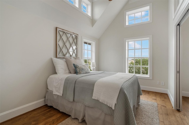bedroom with baseboards, multiple windows, and a high ceiling