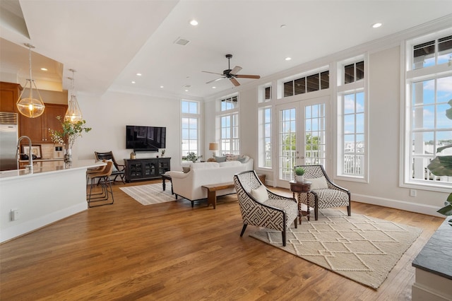living room with a ceiling fan, visible vents, light wood-style floors, ornamental molding, and recessed lighting