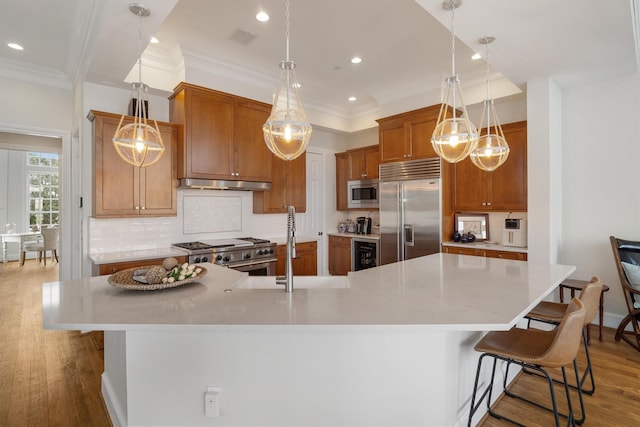 kitchen with built in appliances, tasteful backsplash, under cabinet range hood, wine cooler, and visible vents