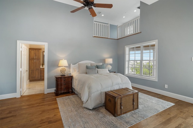 bedroom with baseboards, wood finished floors, and a towering ceiling