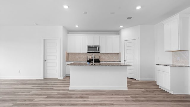 kitchen with dark stone counters, baseboards, appliances with stainless steel finishes, and tasteful backsplash