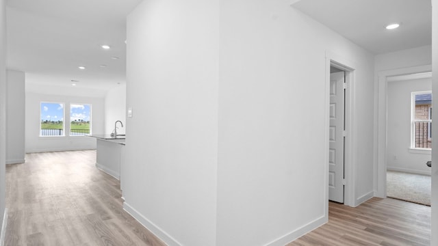 hall with baseboards, recessed lighting, and light wood-style flooring