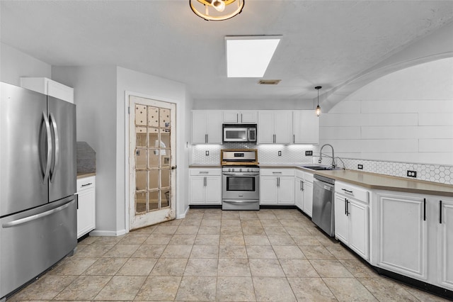 kitchen with a sink, appliances with stainless steel finishes, decorative backsplash, and white cabinetry