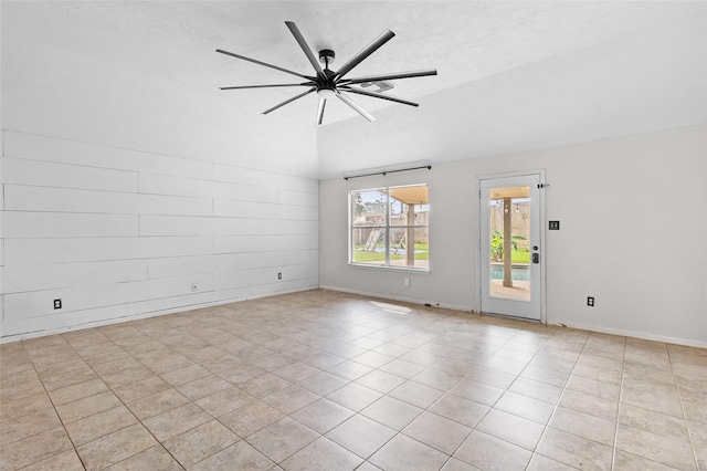 spare room with a ceiling fan, baseboards, vaulted ceiling, and light tile patterned flooring