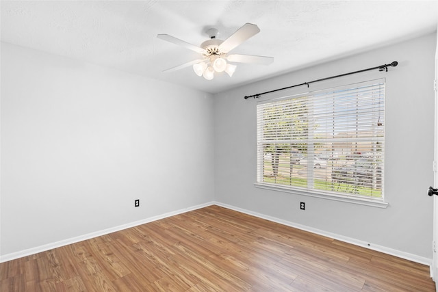 spare room with baseboards, a ceiling fan, and light wood-style flooring
