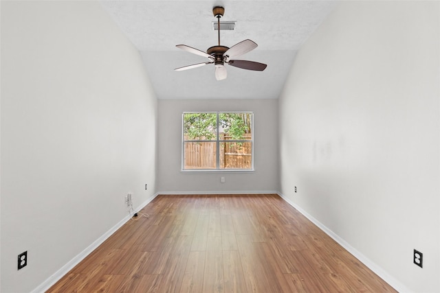 unfurnished room featuring visible vents, lofted ceiling, wood finished floors, baseboards, and a ceiling fan
