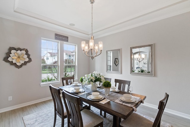 dining room with light wood-style floors, a tray ceiling, and a chandelier