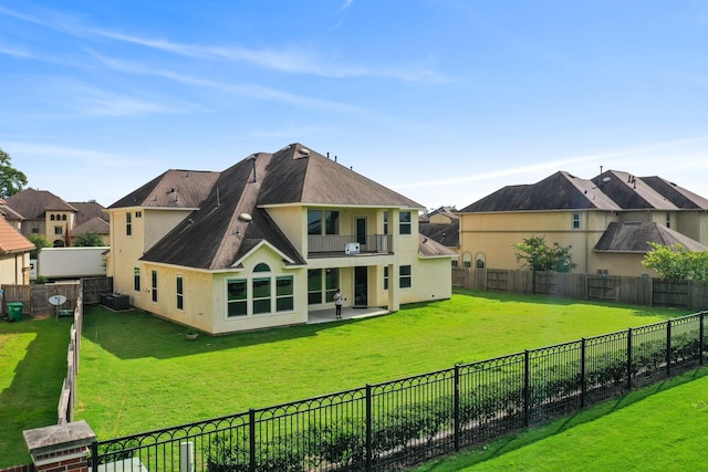 back of house with a lawn, central AC unit, stucco siding, and a balcony