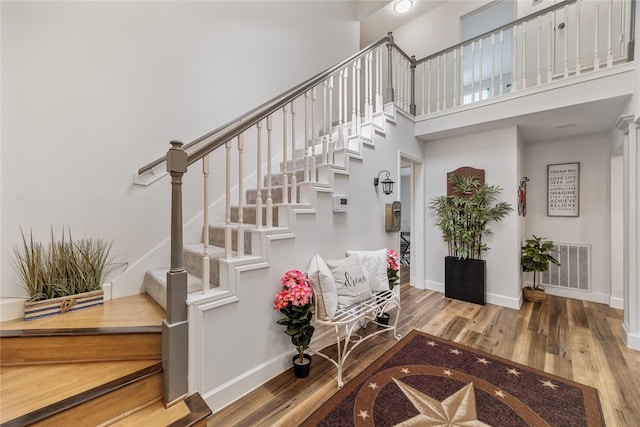 stairway featuring baseboards, visible vents, and wood finished floors