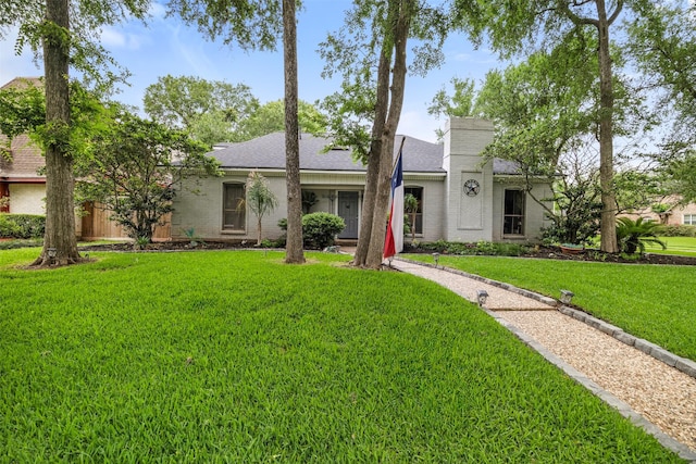 view of front facade with a shingled roof, brick siding, and a front yard