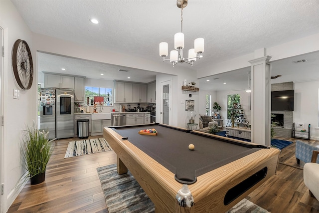 game room with pool table, a textured ceiling, and wood finished floors