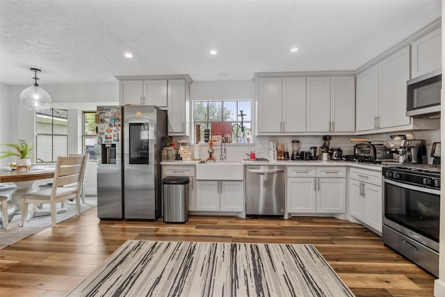 kitchen with light countertops, stainless steel appliances, a sink, and wood finished floors