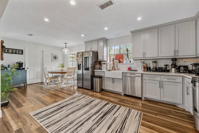 kitchen featuring visible vents, decorative backsplash, light countertops, a textured ceiling, and stainless steel appliances
