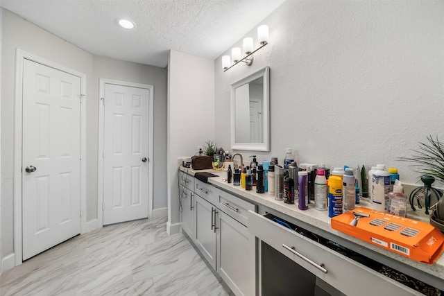 bathroom with vanity, recessed lighting, a textured ceiling, and marble finish floor
