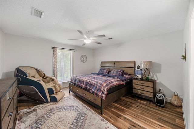 bedroom with ceiling fan, wood finished floors, and visible vents