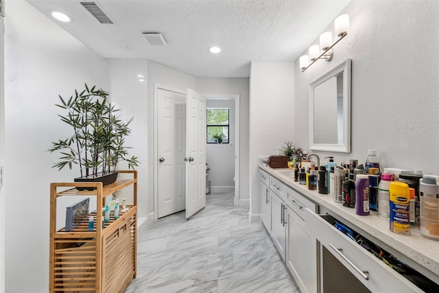 bathroom with vanity, a textured ceiling, marble finish floor, recessed lighting, and visible vents