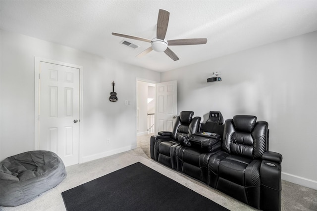 carpeted cinema room with a ceiling fan, baseboards, and visible vents