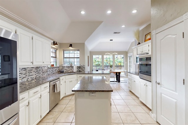kitchen featuring a peninsula, white cabinets, tasteful backsplash, a sink, and stainless steel appliances