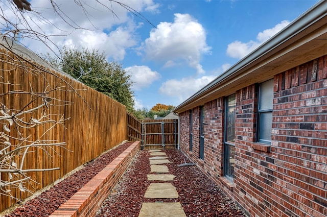 view of property exterior with brick siding and a fenced backyard