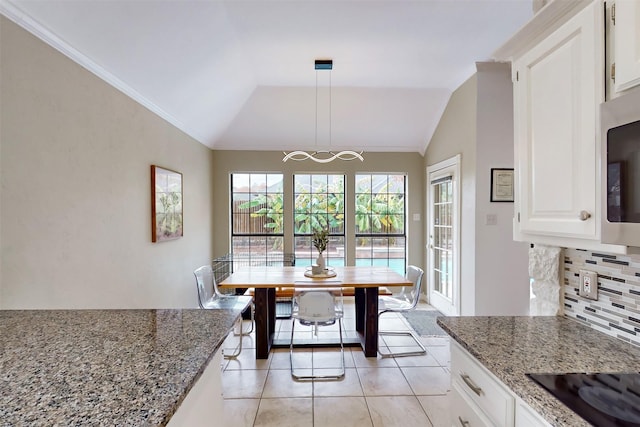 dining space featuring ornamental molding, a chandelier, light tile patterned floors, and vaulted ceiling