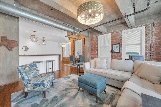204 Travis St Unit 4A, Houston, TX 77002 - living room featuring brick wall, an inviting chandelier, wood finished floors, and visible vents