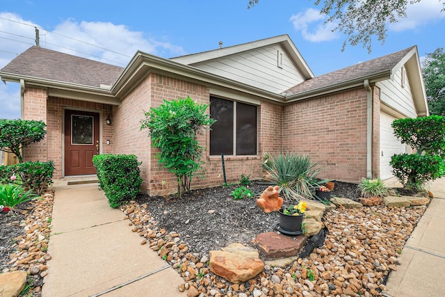 ranch-style house with brick siding, an attached garage, and a shingled roof