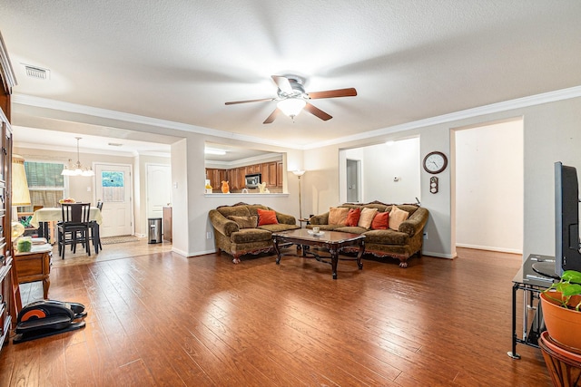 living area featuring visible vents, dark wood-style flooring, ceiling fan with notable chandelier, and baseboards