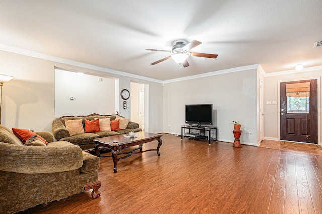 living room featuring a ceiling fan, visible vents, wood finished floors, baseboards, and ornamental molding