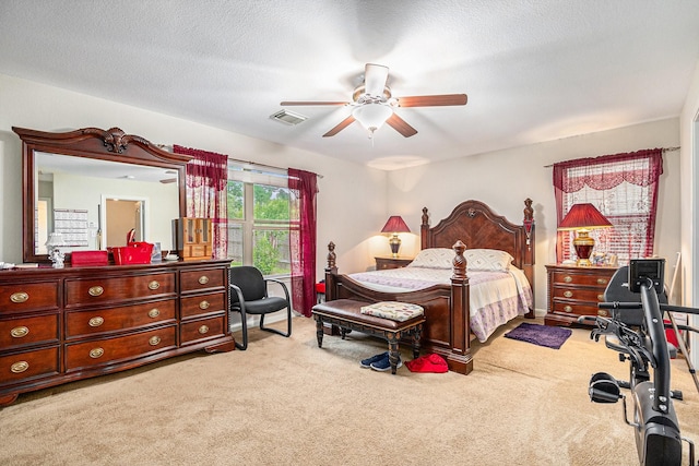bedroom with ceiling fan, carpet flooring, a textured ceiling, and visible vents