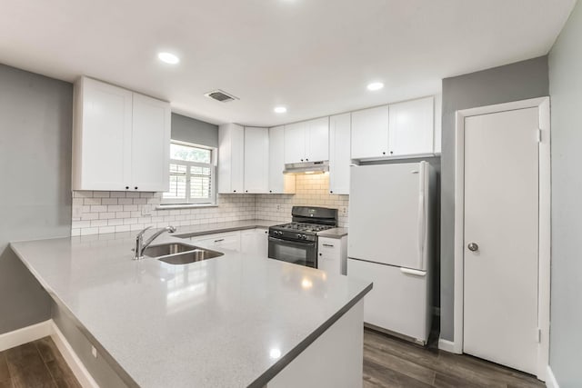 kitchen with visible vents, a sink, freestanding refrigerator, black range with gas stovetop, and a peninsula