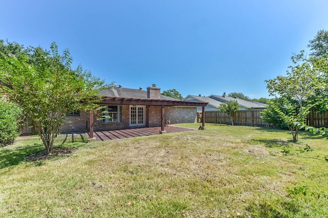 exterior space with brick siding, a fenced backyard, a lawn, and french doors