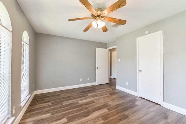 unfurnished bedroom with ceiling fan, baseboards, visible vents, and wood finished floors