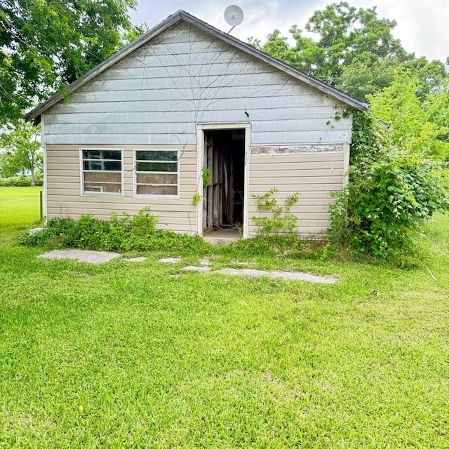 rear view of house featuring an outbuilding and a yard